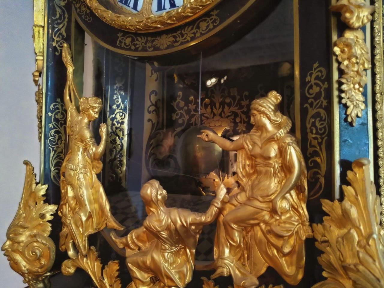 A clock with golden statuettes of the three Fates (Moirai) holding a thread